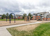 Thumbnail 14 of 20 - A playground with a blue swing set in front of apartment buildings.