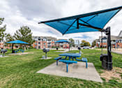 Thumbnail 12 of 20 - A blue picnic table is under a blue canopy in a park.