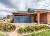 Thumbnail 20 of 20 - A red brick house with a black garage door.