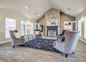 Thumbnail 7 of 20 - A living room with a stone fireplace and a large chair.