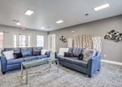 Thumbnail 5 of 20 - A living room with a blue couch and a glass coffee table.