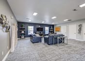 Thumbnail 6 of 20 - A spacious room with a blue couch and a desk.
