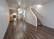 Thumbnail 10 of 15 - A long hallway with a staircase and a ceiling fan.
