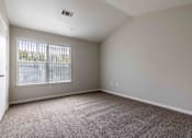 Thumbnail 17 of 22 - A room with a carpeted floor and a window with blinds.