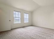 Thumbnail 21 of 22 - A room with carpeted floor, two windows, and a door.