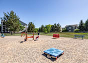 Thumbnail 4 of 22 - A playground with a blue sandbox in the foreground and a red slide in the background.