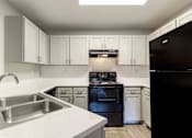 Thumbnail 14 of 22 - A kitchen with black appliances and white cabinets.