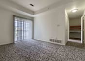 Thumbnail 16 of 22 - A large, empty room with a carpeted floor and a sliding glass door leading outside.