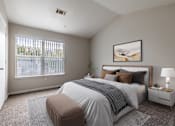 Thumbnail 9 of 22 - A bedroom with a large bed, a nightstand, and a window with blinds.
