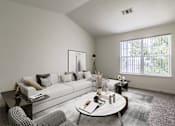 Thumbnail 7 of 22 - A modern living room with a grey sofa, a round coffee table, and a large window.