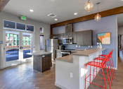 Thumbnail 1 of 8 - A kitchen with a white island and red chairs.