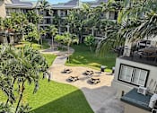 Thumbnail 4 of 20 - A courtyard with a lawn and a building in the background.