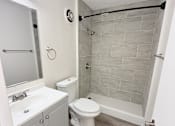 Thumbnail 14 of 15 - A white bathroom with a toilet, sink, and shower.