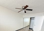 Thumbnail 12 of 15 - A room with a ceiling fan and wooden flooring.