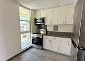 Thumbnail 10 of 15 - A kitchen with white cabinets and a stainless steel refrigerator.