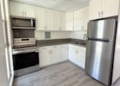 Thumbnail 9 of 15 - A kitchen with a refrigerator, oven, and microwave.