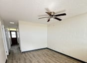Thumbnail 8 of 15 - A room with a ceiling fan and wooden flooring.