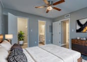 Thumbnail 2 of 22 - A bedroom with a white bed and a ceiling fan.