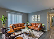 Thumbnail 1 of 22 - A living room with a brown leather couch and a glass coffee table.