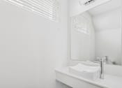 Thumbnail 24 of 32 - A white sink in a bathroom with a mirror and air conditioner above it.
