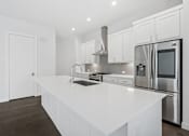 Thumbnail 15 of 32 - A modern kitchen with white cabinets and stainless steel appliances.