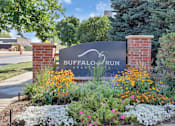 Thumbnail 11 of 21 - A sign for Buffalo Run Apartments is surrounded by flowers.