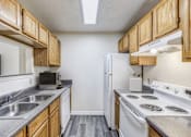 Thumbnail 5 of 30 - A kitchen with a white refrigerator, white stove, and wooden cabinets.