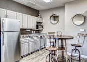 Thumbnail 29 of 30 - A kitchen with a refrigerator, sink, and bar stools.