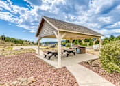 Thumbnail 24 of 30 - A pavilion with a picnic table is surrounded by gravel and a concrete walkway.