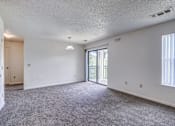Thumbnail 17 of 30 - A room with a carpeted floor and a sliding glass door leading outside.