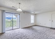 Thumbnail 18 of 30 - A spacious room with a sliding glass door leading to a balcony.