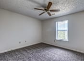 Thumbnail 19 of 30 - A room with a ceiling fan and a window letting in natural light.