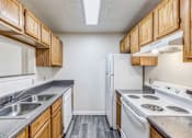 Thumbnail 11 of 30 - A kitchen with white appliances and wooden cabinets.