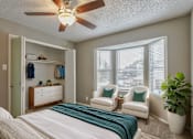 Thumbnail 5 of 19 - A bedroom with a bed, two chairs, a ceiling fan, and a potted plant.