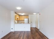 Thumbnail 5 of 6 - A kitchen with white cabinets and a white island in the middle of a room with wooden floors.