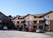 Thumbnail 2 of 6 - an apartment building with cars parked in front of it