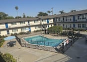 Thumbnail 7 of 9 - A pool surrounded by a fence and a building in the background.