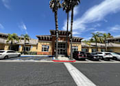 Thumbnail 1 of 18 - Irvine Inn parking lot with a white car parked in front of a building with a palm tree in front of it.