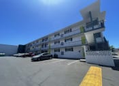 Thumbnail 24 of 27 - a large white apartment building with cars parked in front of it