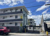 Thumbnail 19 of 27 - an apartment building with a red car parked in front of it