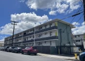 Thumbnail 21 of 27 - an apartment building on a city street with parked cars