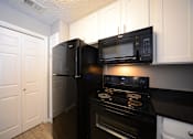 Thumbnail 36 of 47 - The Trellis at Lake Highlands kitchen area with refrigerator, stove, and cabinets 