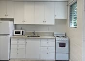 Thumbnail 1 of 13 - A kitchen with white appliances and cabinets.