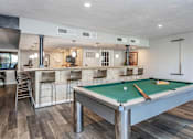 Thumbnail 17 of 41 - A pool table is in the middle of a room with a bar area.