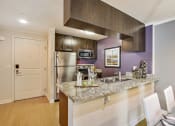 Thumbnail 4 of 23 - a kitchen with a granite counter top and a stainless steel refrigerator
