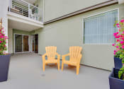 Thumbnail 17 of 23 - a patio with two chairs and flowers in front of a building