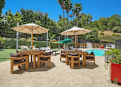 Thumbnail 16 of 53 - A patio with a table and chairs and umbrellas.