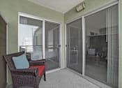 Thumbnail 50 of 53 - A chair with a red cushion and a blue pillow is in front of a glass door.
