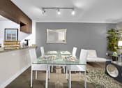 Thumbnail 32 of 53 - A modern dining room with a glass table and white chairs.