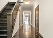 Thumbnail 11 of 13 - A long hallway with a staircase on the left side.